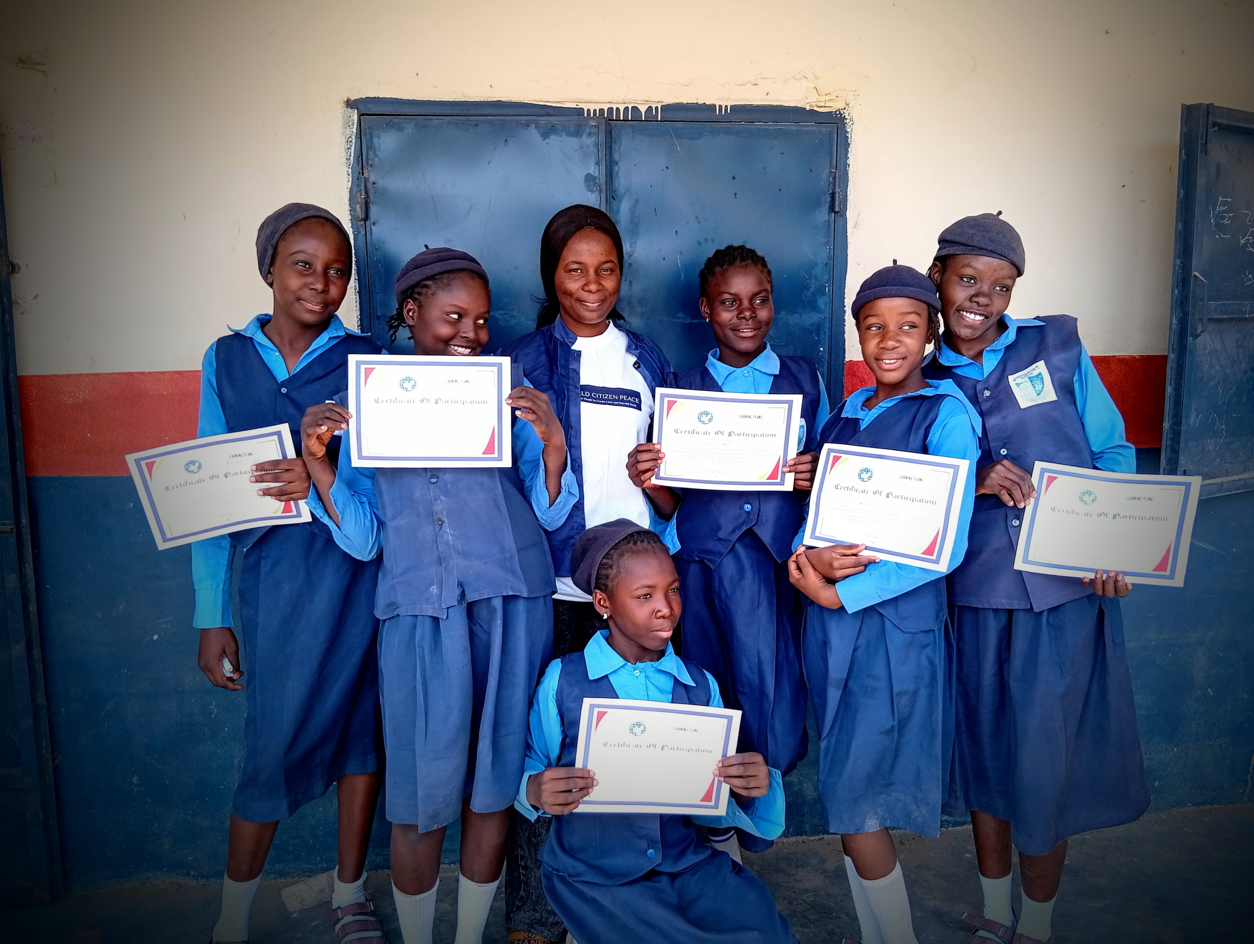 A group of school children in uniform in Nigeria holding peace certificates.