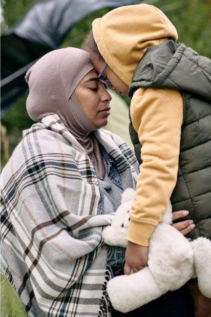 Image of woman touching foreheads with a young child holding a teddy bear.