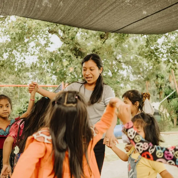 Image of a woman singing with young girls dancing around her